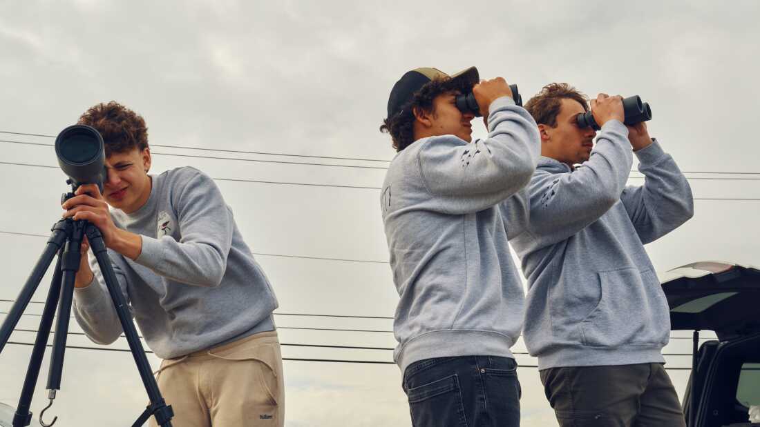 Teammates Otys Train, 16, (left), Zade Pacetti, 16, and Jack Trojan, 17, look through a scope and binoculars as they aim to identify as many bird species as possible during the World Series of Birding at Malibu Beach Wildlife Management Area in New Jersey.